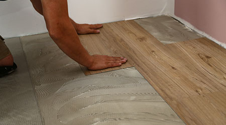 worker installing new vinyl tile floor 