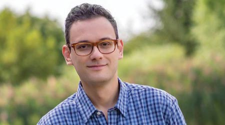 Man in glasses smirks with folded hands