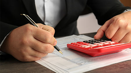 man sitting at table with calculator, document and pen.