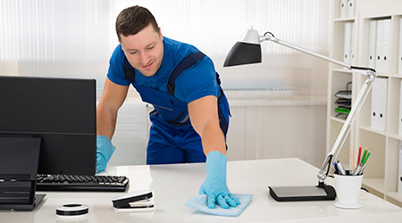 Mid adult male worker cleaning desk with sponge at office