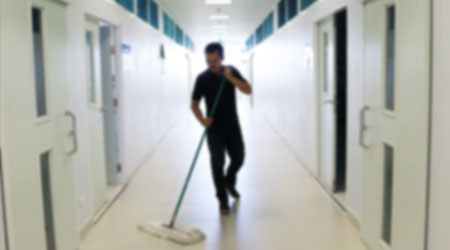 Asian janitor man mopping floor in office building or walkway school