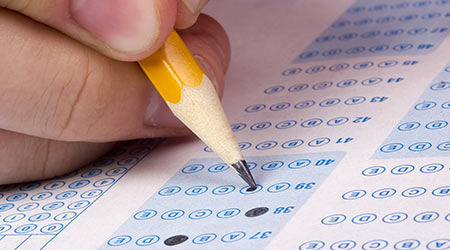 A person filling out a bubble sheet with a pencil during an exam