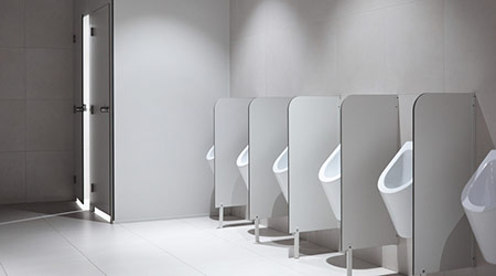 Row of clean porcelain sensor-operated male urinals with partitions