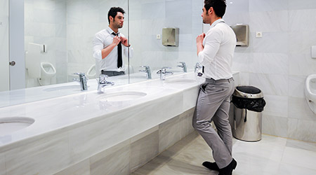 Man getting dressed in a public restroom with mirror