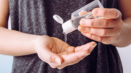 A woman putting on hand sanitizer