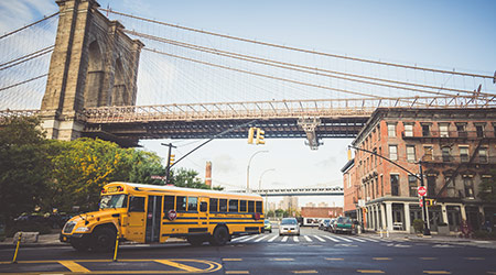 Brooklyn Bridge, New York, USA - 21 October, 2016: School bus riding on road on bridge background.