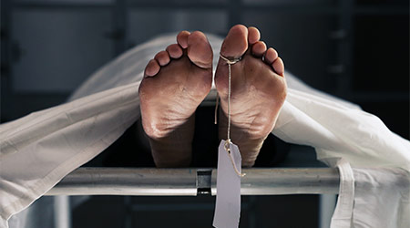 a corpse under a white sheet at the morgue. corpse with toe tag
