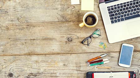Mix of office supplies and gadgets on a wooden table background. View from above.