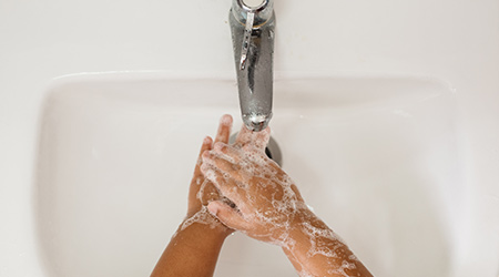 funny and joyful baby shows his soapy palms. Copy-space. Prevention of diseases with viruses and flu. The exposure time of the soap is at least 20 seconds. Studio photo, banner, isolated.