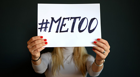 A woman holding up a sign that says "#MeToo"