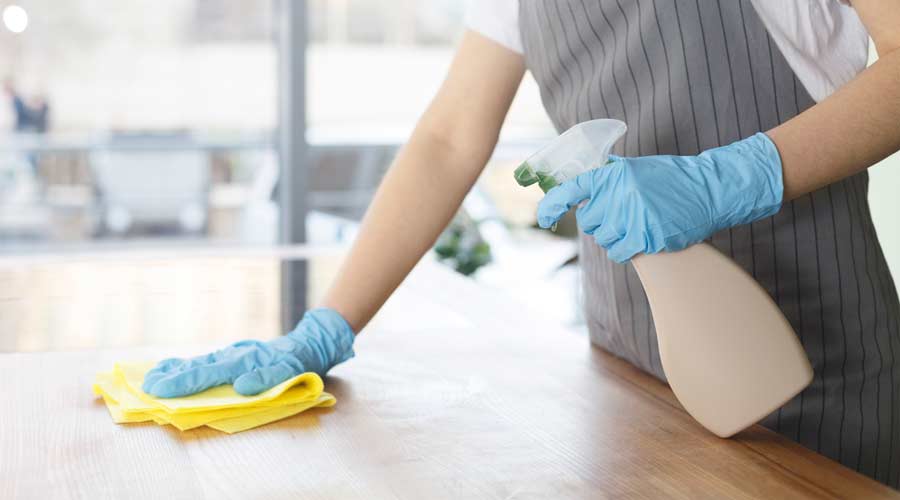 Closeup of female hands in rubber gloves cleaning the table before work on kitchen, eco quarantine cleaning