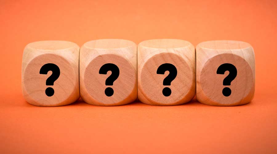 Four wooden blocks with black question marks.
