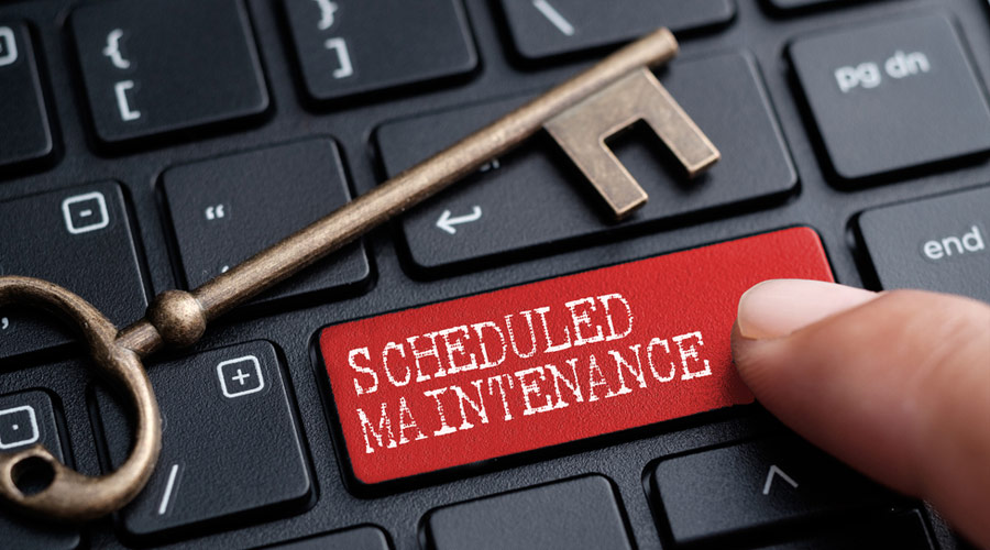 Closed up finger on keyboard with word SCHEDULED MAINTENANCE