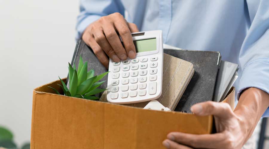 Resignation Concept The man in light blue shirt standing at the desk and putting the calculator and other stuff into the box.