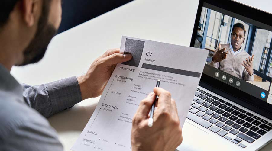 Male indian hr, recruiter or employer holding cv having online virtual job interview meeting with african candidate on video call. Distance remote recruitment conference chat. Over shoulder view.
