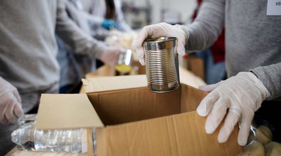 Midsection of group of volunteers in community donation center, food bank and coronavirus concept.