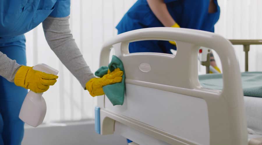 Team of professional janitors using equipment disinfecting hospital ward. Nurses in uniform cleaning furniture in empty clinic room. Healthcare and hygiene concept