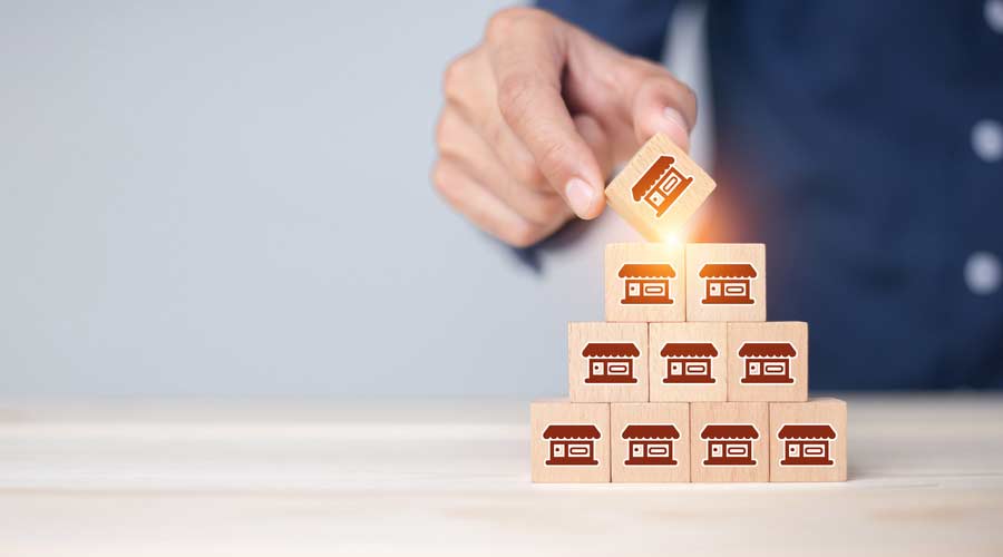 Franchise business,Businessman hand choose wooden blog with franchise marketing icons Store. Franchise business concept