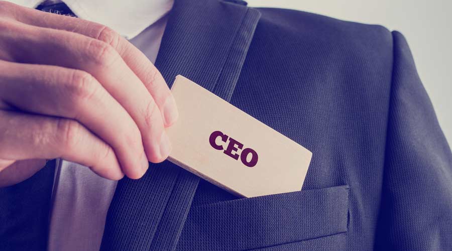 Retro style image of a businessman showing a wooden card reading - CEO - as he withdraws it from the pocket of his suit jacket.
