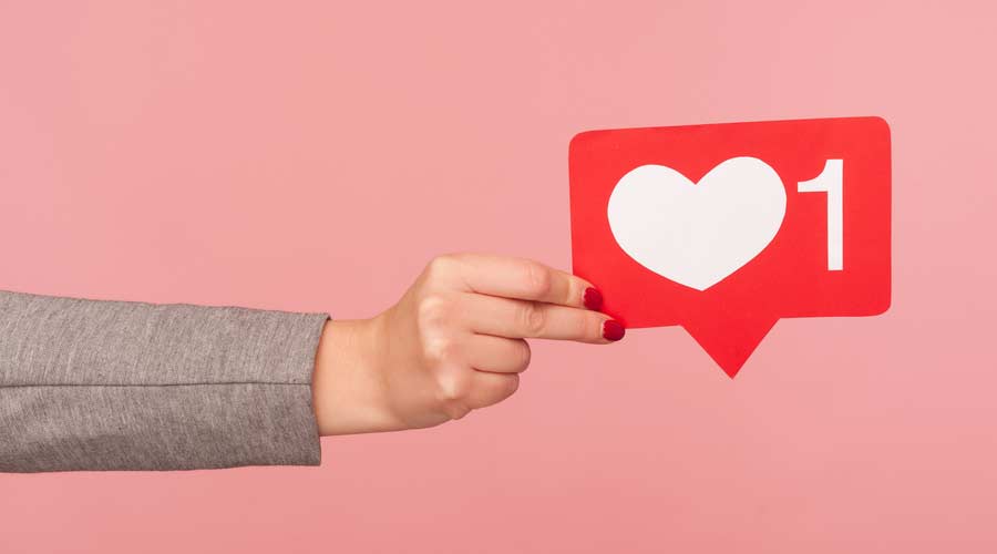 Support interesting web content, push heart button. Closeup of hand holding social media like icon, emoji sign to follow subscribe blog, popular forum. indoor studio shot isolated on pink background
