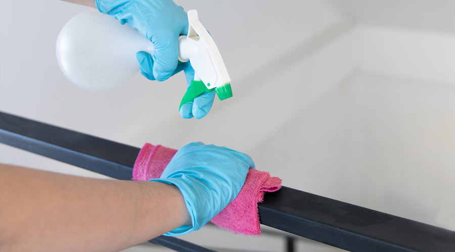 Young Asian male employee uses a towel soaked in alcohol to wipe off the railing or porch, Pathogen prevention or cleaning during virus outbreaks, Cleaning of a restaurant or coffee shop.