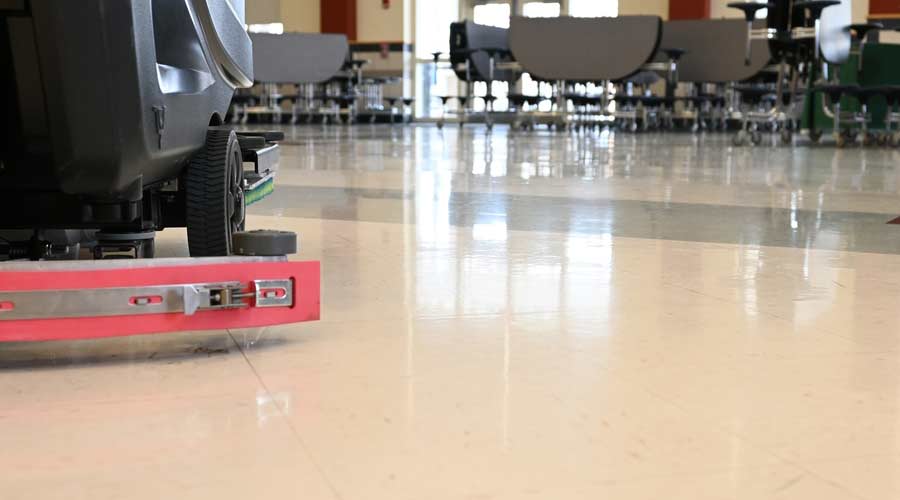 Auto scrubber on a floor in a school cafeteria. Automated floor cleaning machine in public space. Janitorial maintenance