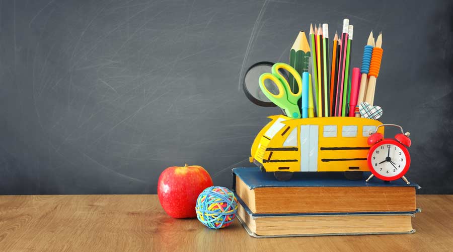 education and back to school concept. pencils stand as bus over wooden desk infront of classroom blackboard