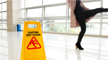 Woman slips next to wet floor sign