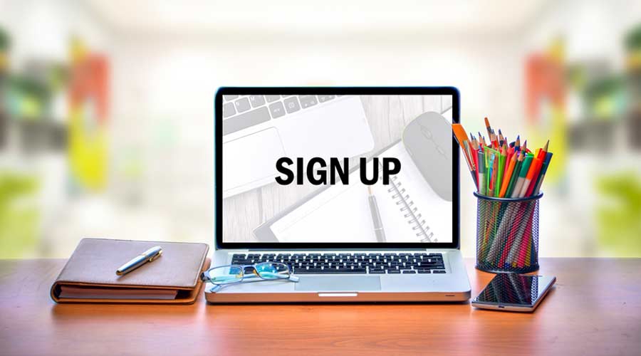 Open laptop with isolated white screen on old wooden desk with text SIGN UP