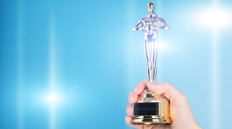 Oscar award, trophy statue in hand on blue background