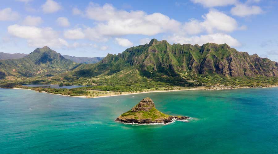 Aerial drone shot of Kualoa mountain range and Chinaman's Hat on Oahu, Hawaii.