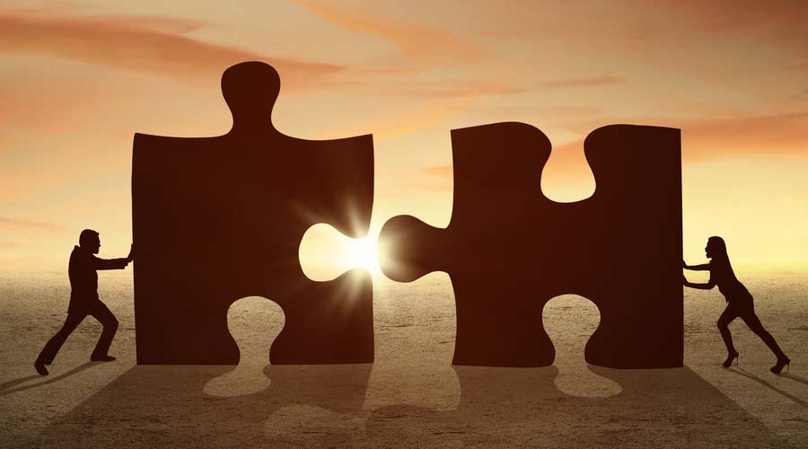 Individuals push two large puzzle pieces together