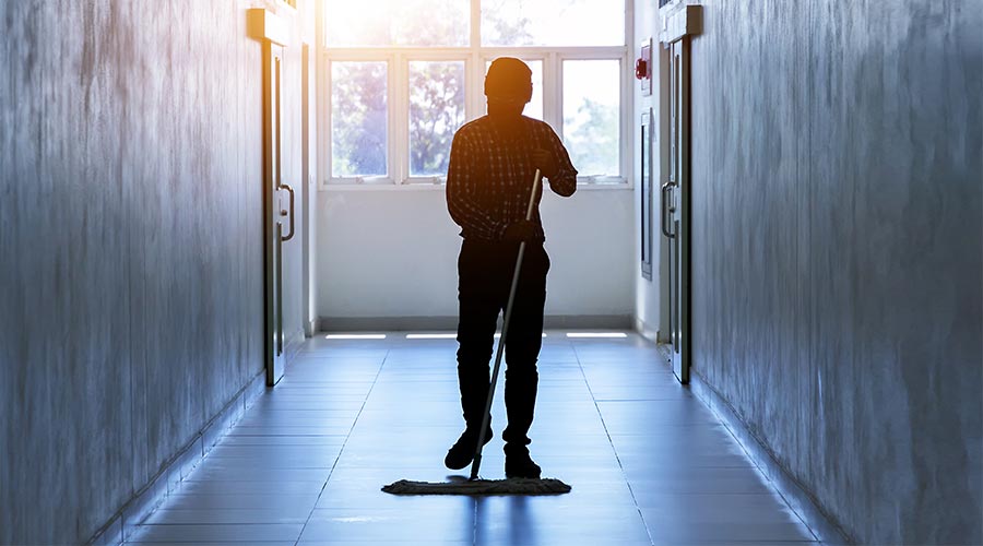 Janitor man mopping floor in dark hallway building or walkway silhouette working job with sun light background. Housekeeper or maid cleaner service concept.