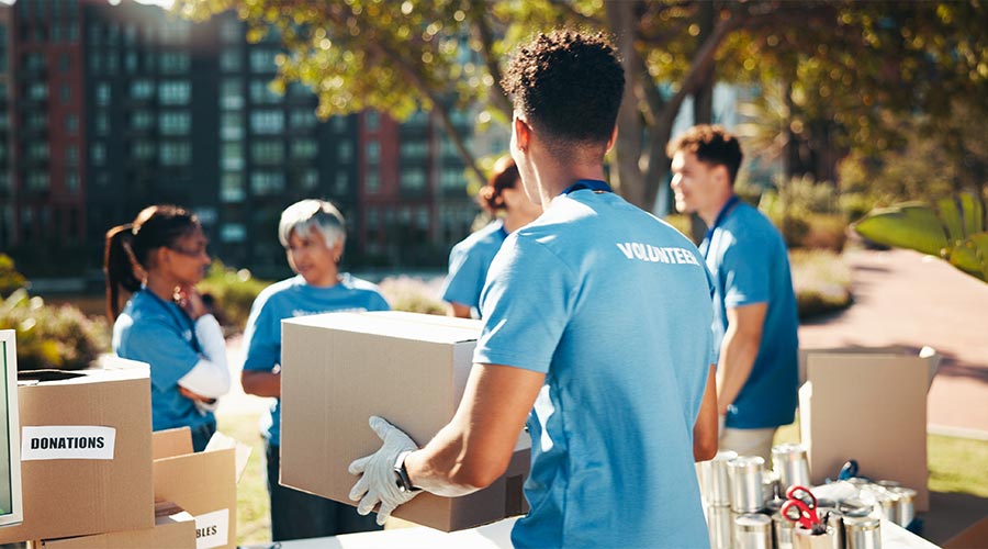 Box, volunteer team and outdoor for donation, help and back for community care. NGO group, man and charity service with package for distribution, food drive and humanitarian aid with poverty supplies