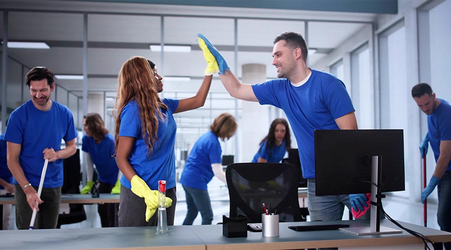 Cleaning team celebrates successful day in corporate office with high-five