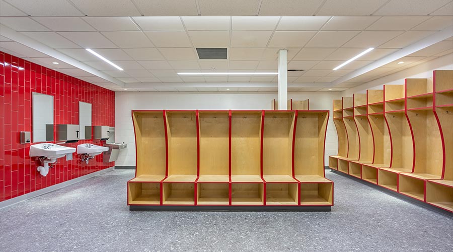 Empty team locker, changing room with traditional open wooden lockers with a red trim.