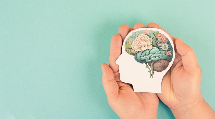 Hands holding paper head, human brain with flowers, self care and mental health concept, positive thinking