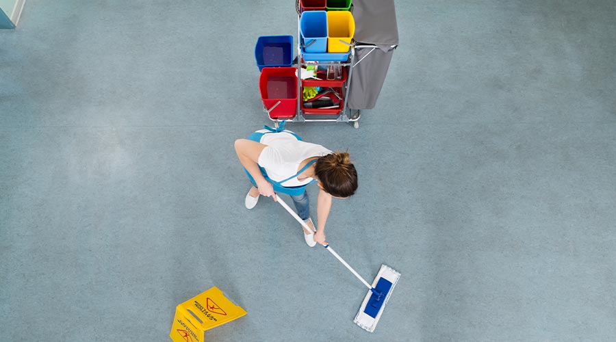 Female Janitor Mopping Floor With Caution Sign