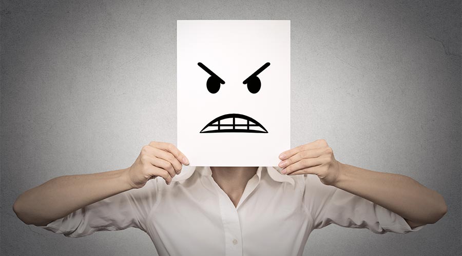 A person with a piece of paper demonstrating anger in front of their face