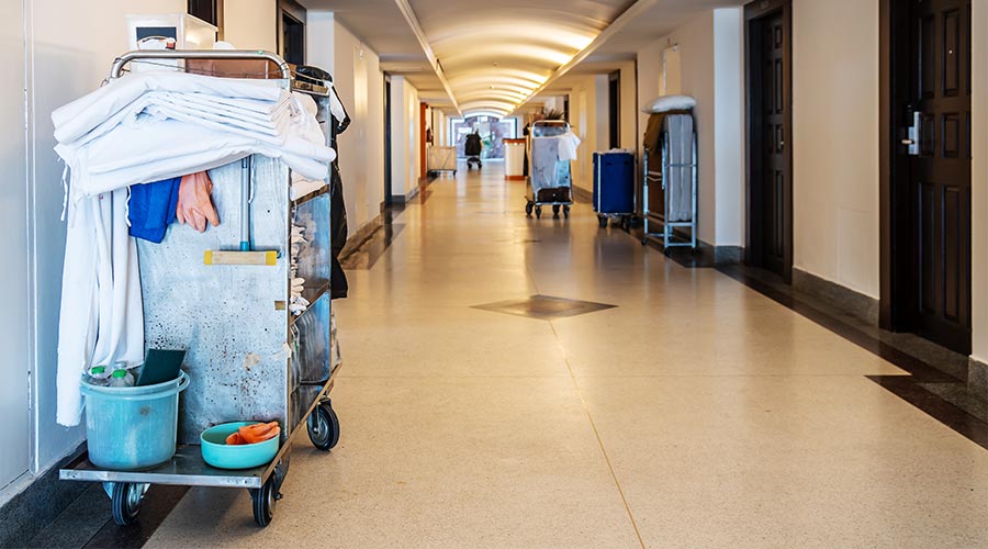 Cleaner pushing trolley in school corridor