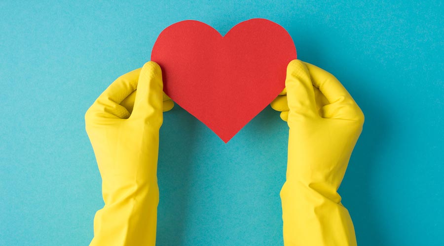 Top view photo of hands in yellow rubber gloves holding red paper heart on isolated pastel blue background with blank space