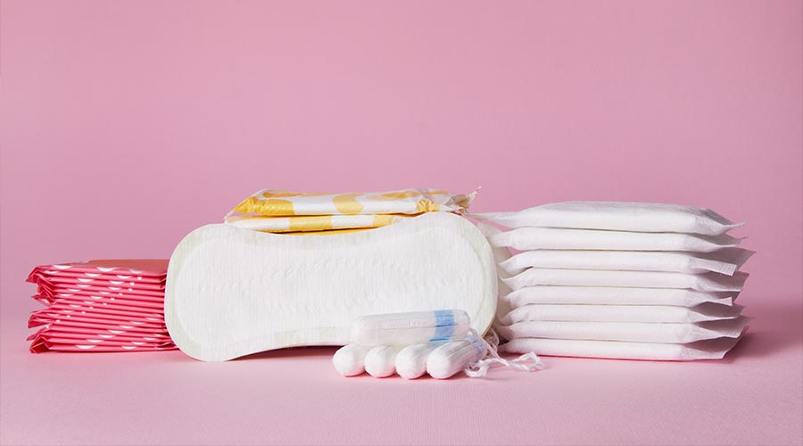 stack of menstrual sanitary cotton pads and tampon on pink background. Feminine hygiene products. copy space.