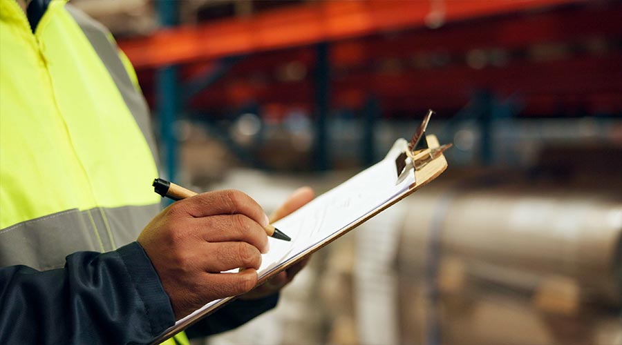Clipboard, hands and inventory with person in warehouse for inspection, stock or quality control. Logistics, storage or supply chain with employee in plant for export and import distribution closeup
