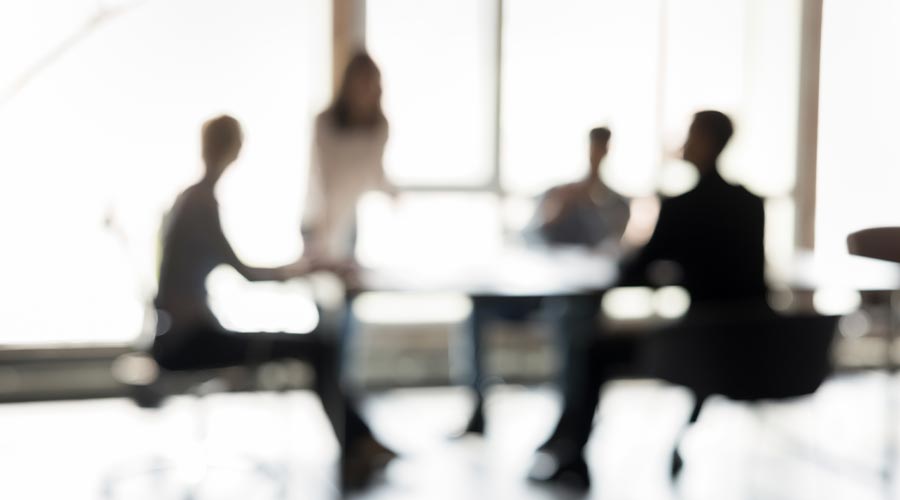 Blurred silhouettes of people participate in business meeting or collaborative discussion, engaged in exchanging ideas, make decisions, strategizing together, gathered in well-lit boardroom. 