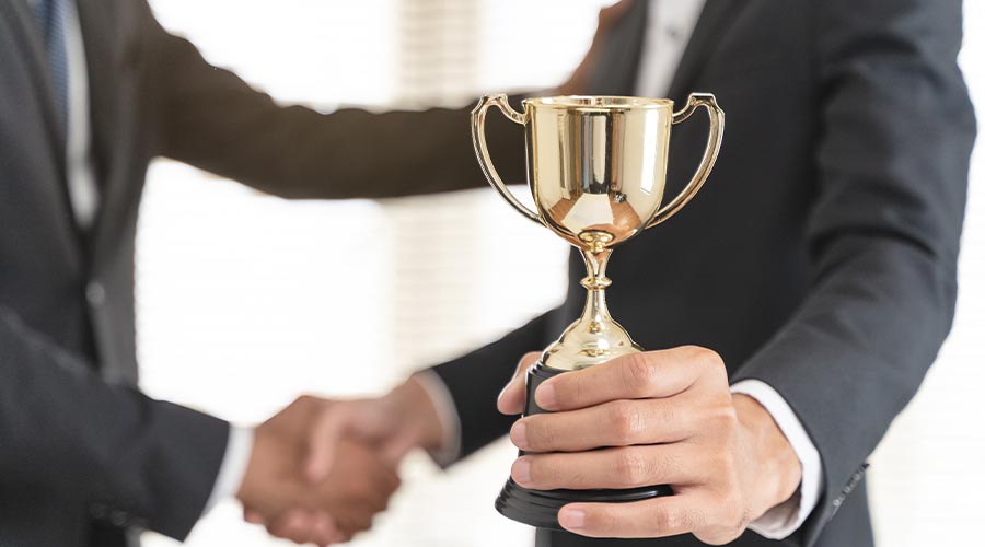 The hands of an employee receiving a golden cup reward from the company manager represent his performance in his career job reward.