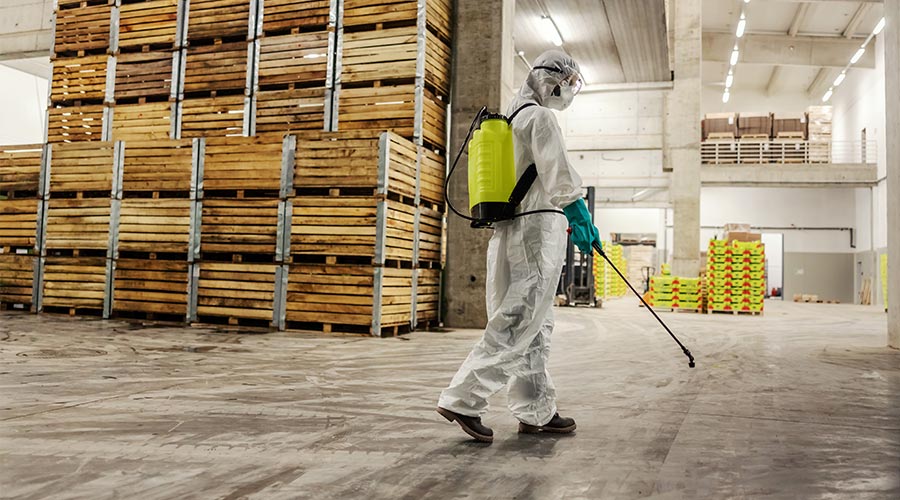 Dedicated expert in white protective uniform with mask and goggle disinfection space with antiseptic spray. Coronavirus control, stop spread infection