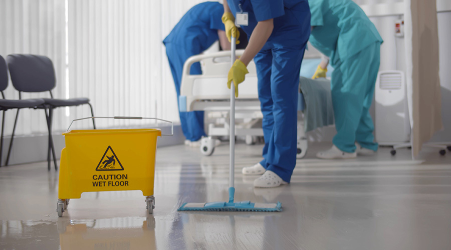 Nurses mopping floor and making bed in empty hospital ward. Medical staff in uniform wiping floor and cleaning intensive care unit in modern clinic