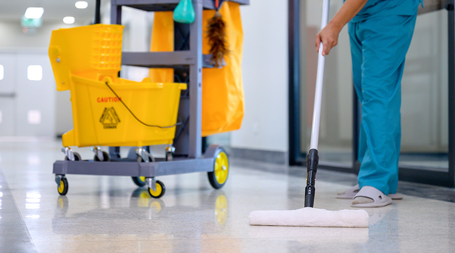 A close-up of a mop cleaning the office floor with a cleaning cart, mop cleaning tools, and equipment made of epoxy flooring