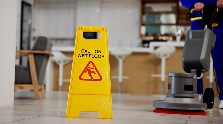 Cleaning, service and caution for wet floor, business and person with equipment for hygiene or sign. Board, information and warning for safety, disinfection and routine for sanitation of coffee shop